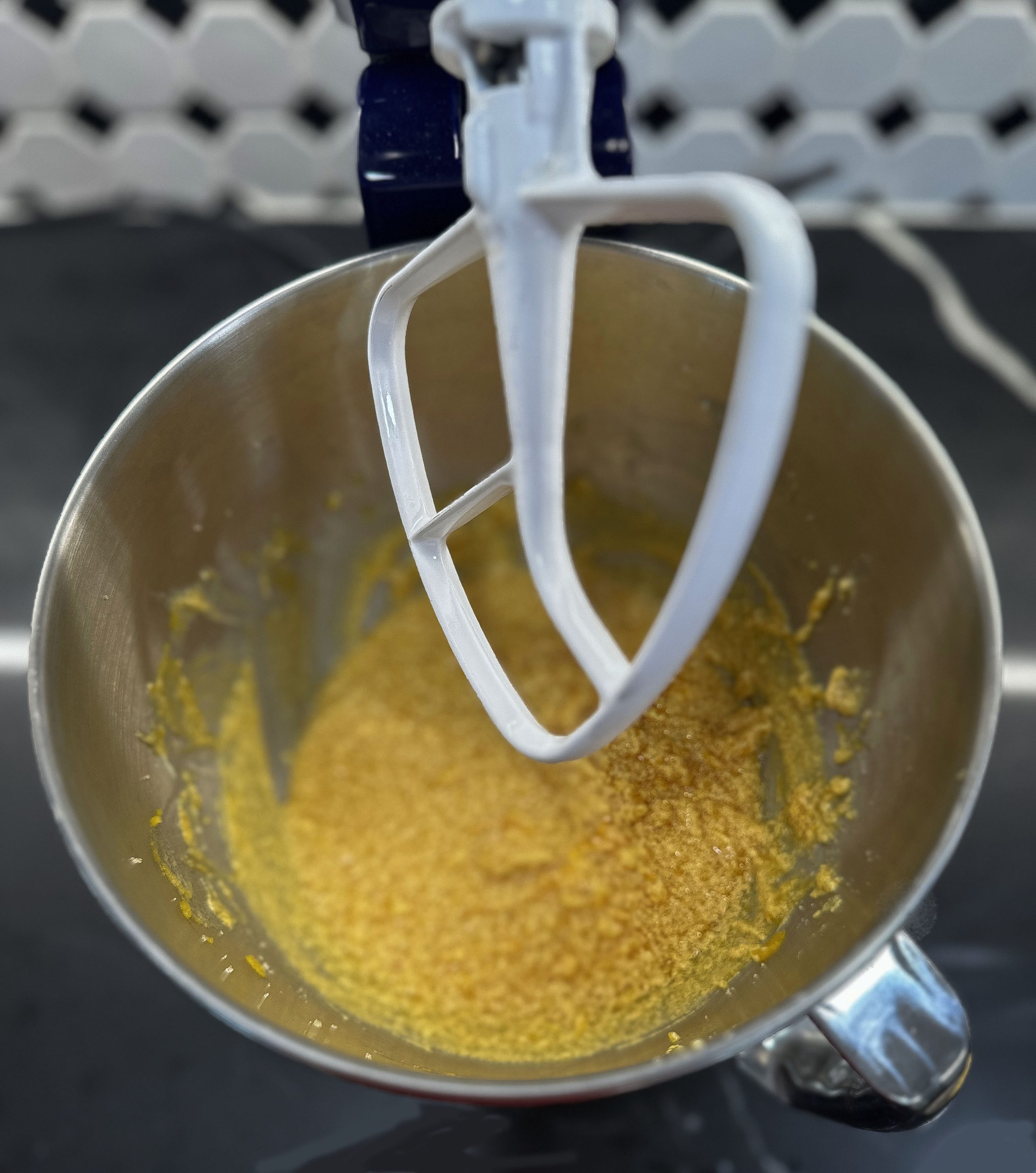 This image shows the initial stage of mixing pumpkin spice cookie dough in a stand mixer, with the wet ingredients being blended in a metal mixing bowl.