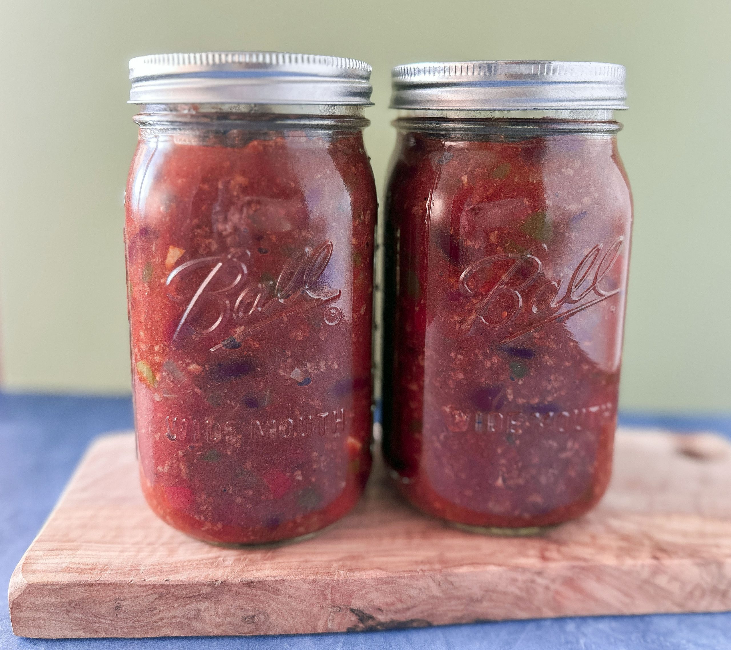 Two mason jars filled with homemade chili, sealed and ready for storage.